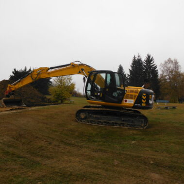 Bagger beim Einsatz auf einer Wiese