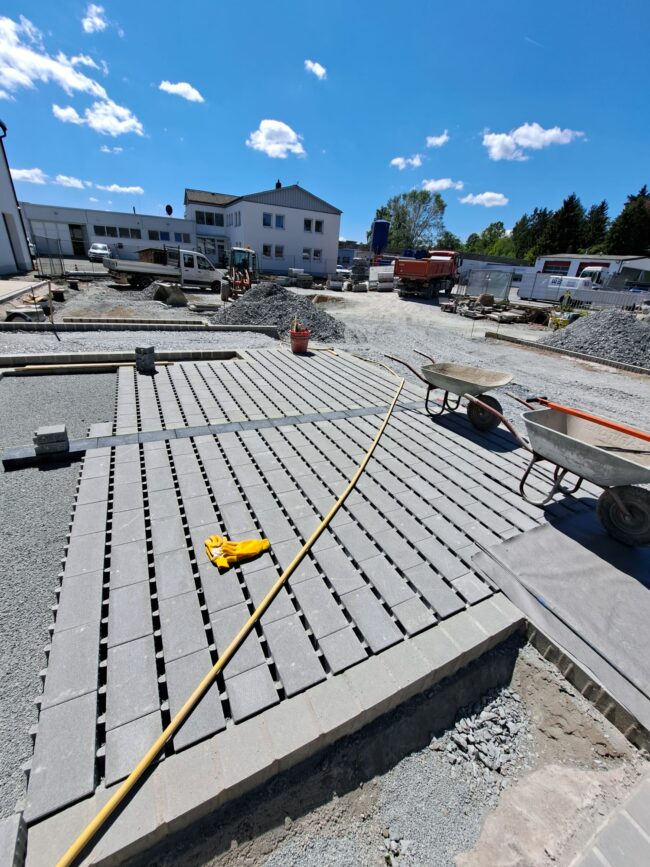Baustelle mit frisch verlegten Betonpflastersteinen in rechteckigem Muster.