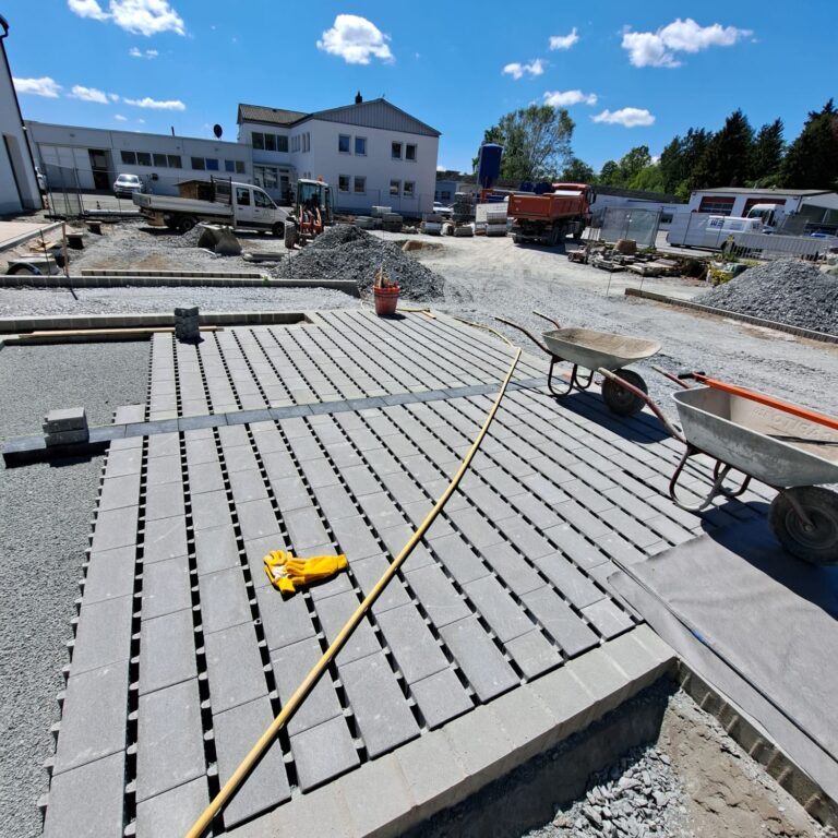 Baustelle mit frisch verlegten Betonpflastersteinen in rechteckigem Muster.